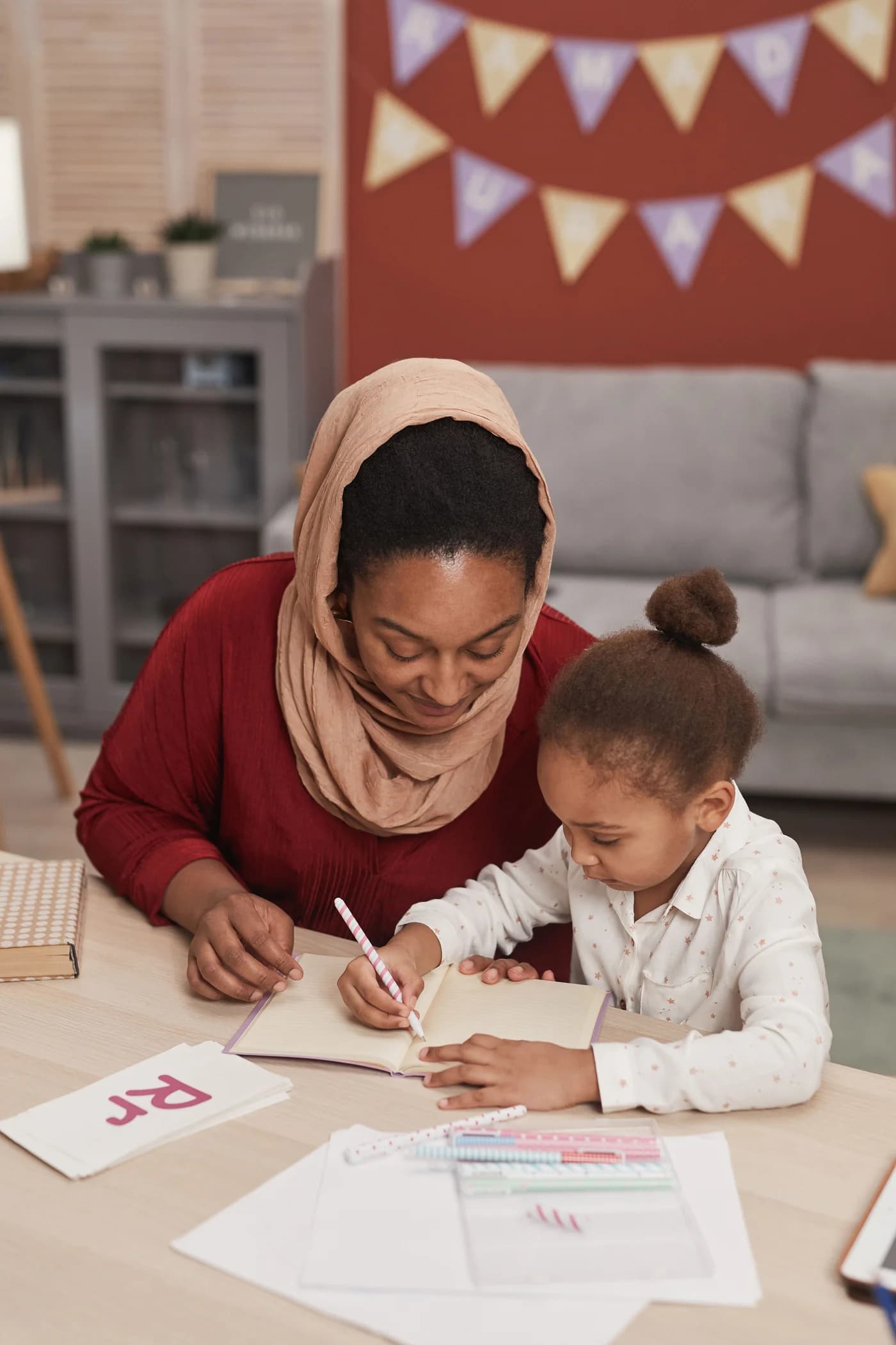 A mother and young daughter sharing a quiet moment over a notebook at home. Illustrative photograph.